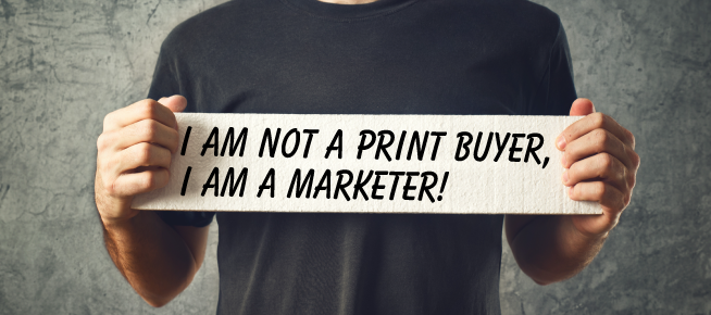 Person holding a sign that reads "I AM NOT A PRINT BUYER, I AM A MARKETER!" emphasizing the shift from traditional print buying to a marketing-focused perspective in the print industry.