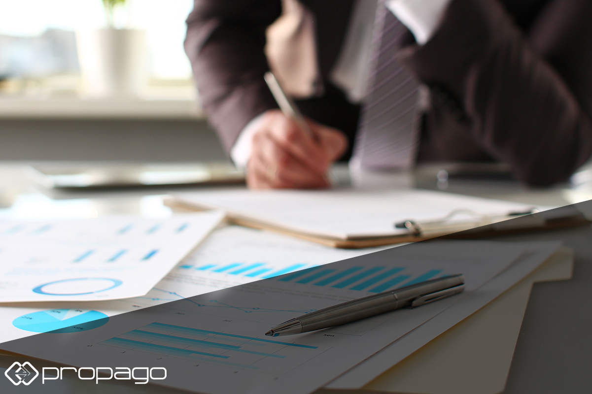 Business professional reviewing documents and charts on a desk, emphasizing web-to-print solutions during economic slowdown.