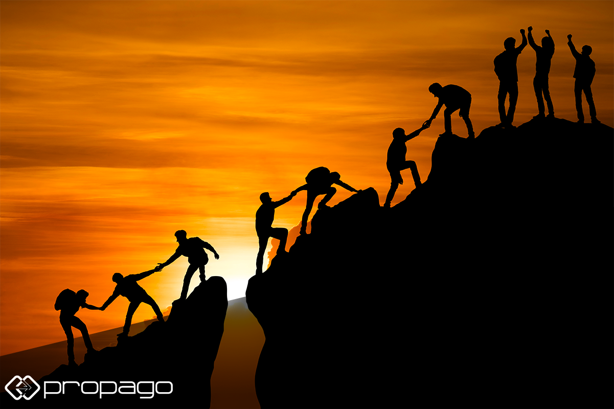Silhouettes of people climbing a mountain at sunset, symbolizing teamwork and collaboration, with Propago logo in the foreground, emphasizing the importance of internal web-to-print team dynamics.